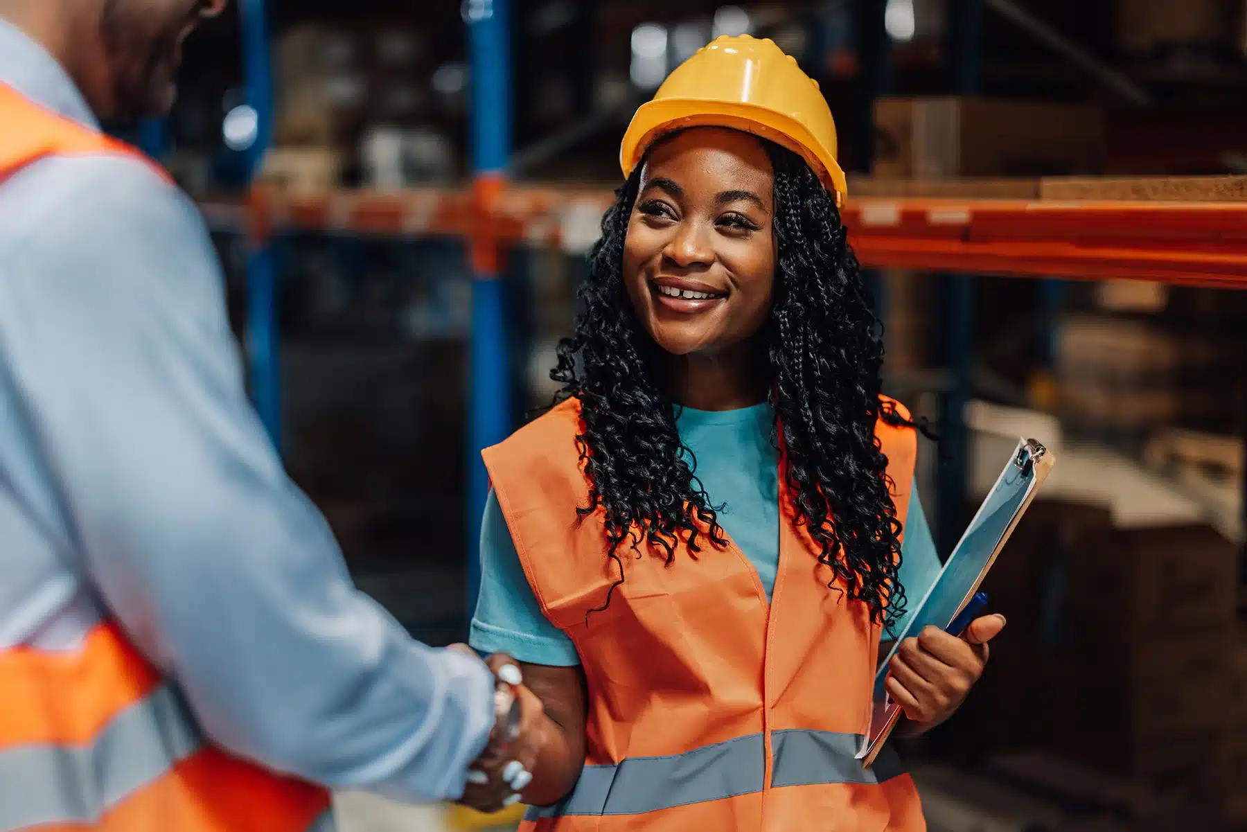 Female warehouse worker shaking hands with manager