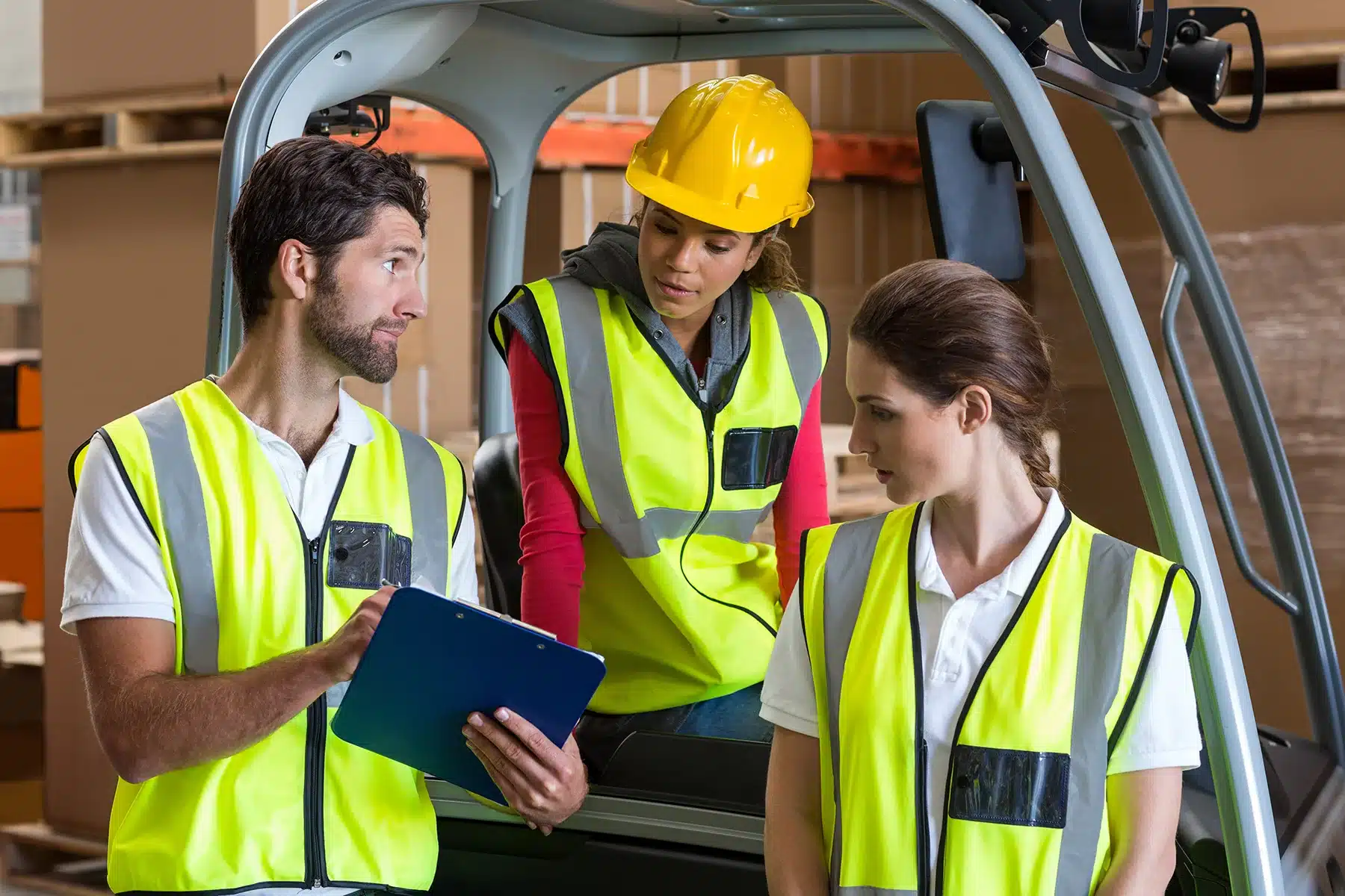 Warehouse workers talking with forklift driver